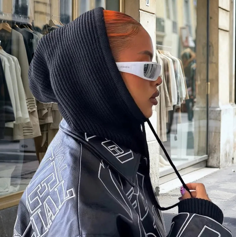 Passamontagna invernale donna nera indossata da una donna con i capelli raccolti, abbigliamento streetwear e occhiali bianchi, fotografata in città davanti a un negozio - Spazio Passamontagna.