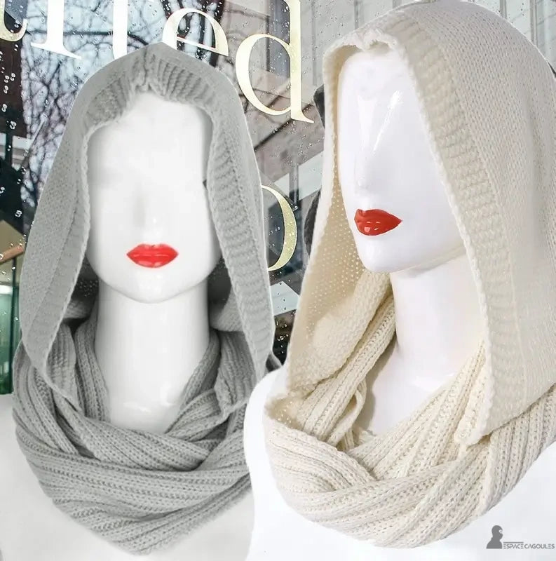 Cagoule femme mode grise et beige moderne en laine tricotée présentée sur mannequin avec reflet de vitrine citadine en arrière-plan