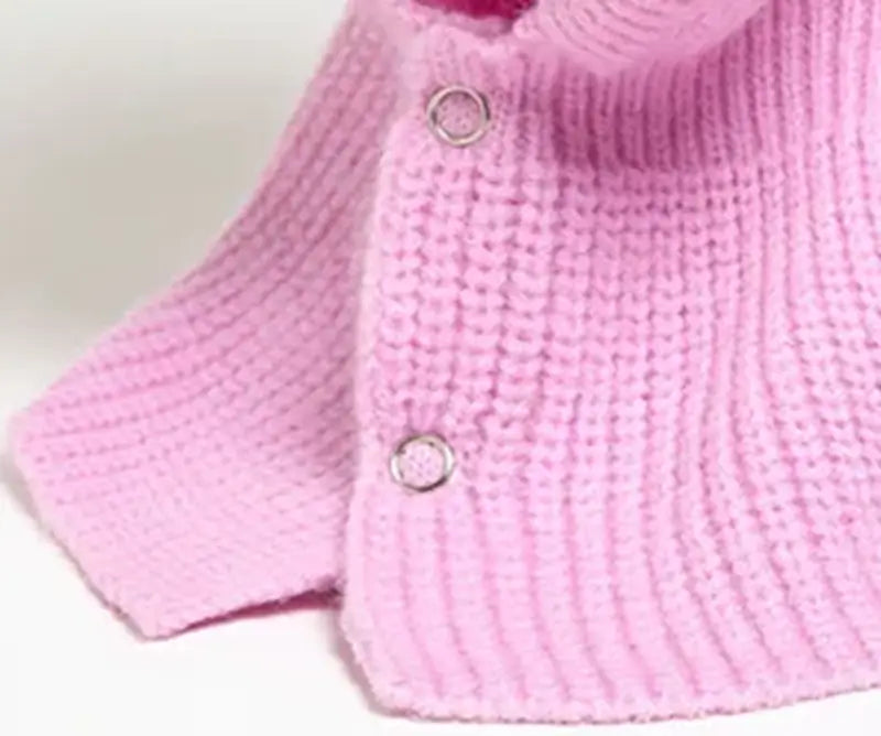 Détail d'une cagoule femme rose en tricot avec boutons sur le col, offrant un ajustement pratique et un look sophistiqué.
