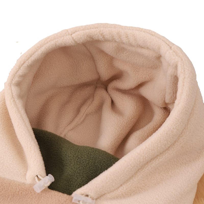 Gros plan sur l'intérieur d'une cagoule grand froid enfant en polaire beige avec doublure verte, offrant chaleur et confort pour l'hiver.