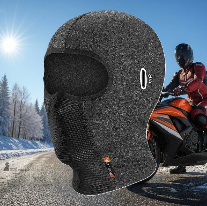 Cagoule hiver moto – Cagoule grise en situation sur route hivernale ensoleillée avec motard en arrière‑plan - Espace Cagoules