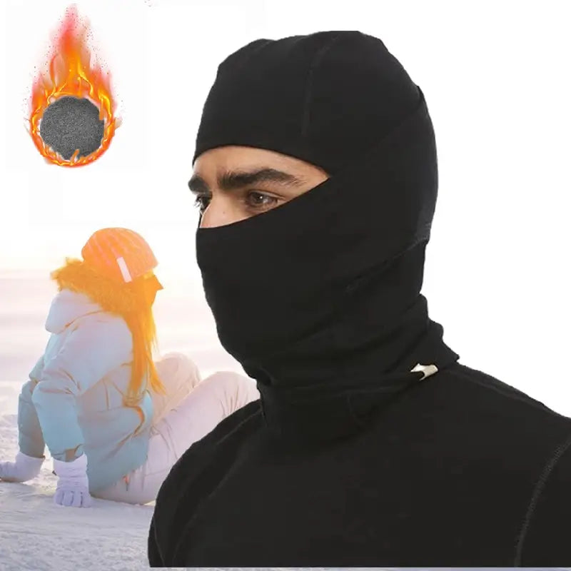 Homme portant une cagoule en laine mérinos noire, dans un environnement enneigé, couvrant parfaitement le visage pour une chaleur optimale en plein hiver. 