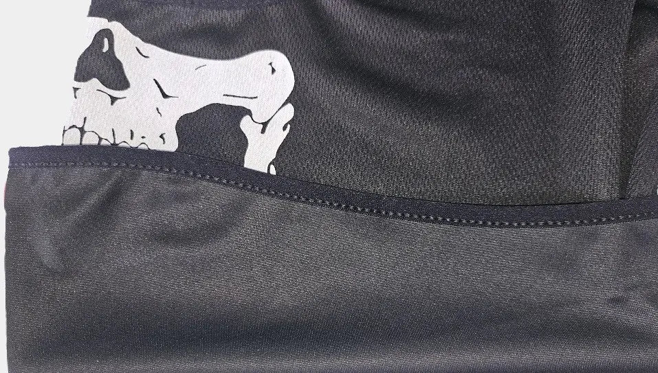 Zoom sur une cagoule militaire noire en tissu respirant avec un motif de tête de mort blanche imprimée, mettant en avant des détails précis du crâne sur un fond sobre. Idéal pour les activités outdoor ou les déguisements tactiques.