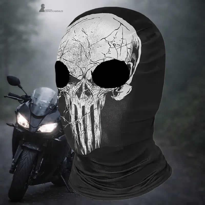 Black microfiber motorcycle balaclava with 2 holes, featuring a white skull design, viewed in three-quarters on the road with a motorcycle in the background - Cagoules Space.