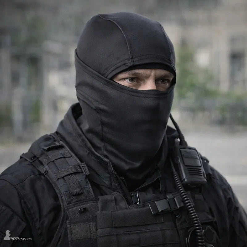 Schwarze Sturmhaube mit einem Loch aus dehnbarem schwarzem Fleece, getragen von einem Mann in taktischer Kleidung, Außenansicht auf die Brust in urbaner Umgebung - Bereich Sturmhauben.