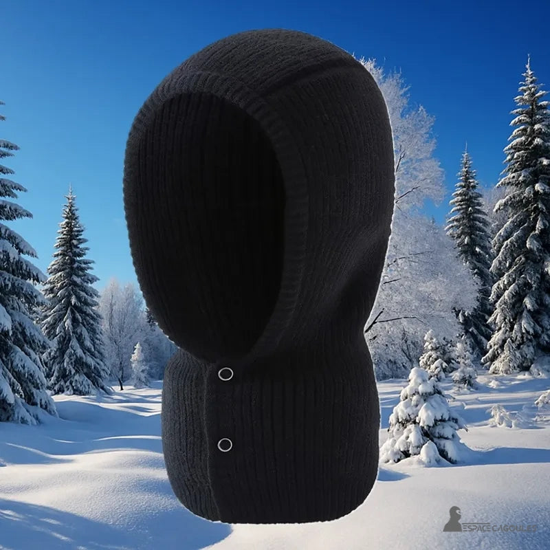 Cagoule Noire Femme en maille épaisse photographiée sur fond de forêt enneigée, idéale pour affronter l’hiver avec sobriété