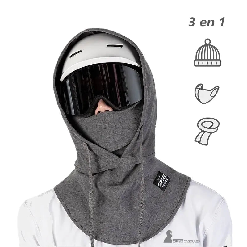 Cagoule par dessus casque ski portée sous un casque blanc avec masque de ski, modèle 3 en 1 couvrant tête, cou et menton, idéale pour les sports d’hiver.