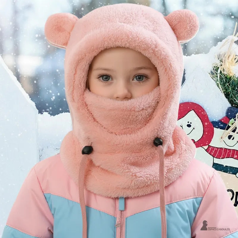 Cagoule polaire enfant 4 à 10 ans rose portée par une fillette vêtue d’une veste de ski, décor hivernal enneigé à l’arrière-plan – Espace Cagoules