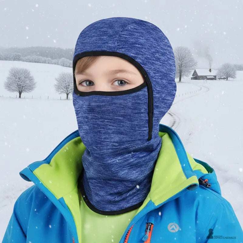Skidmask för barn under hjälm, bärs av ett barn utomhus i vintermiljö, tillverkad av andningsbart och tunt fleece-material, helform som täcker huvud och hals, framsidan i snöig miljö - Cagoules Utrymme.
