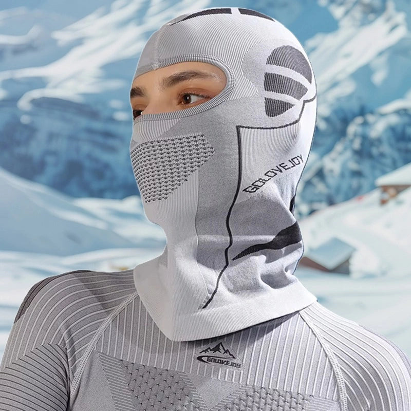 Femme en montagne portant une cagoule ski femme gris clair, ajustée sous un pull thermique, offrant une protection efficace contre le froid et le vent.