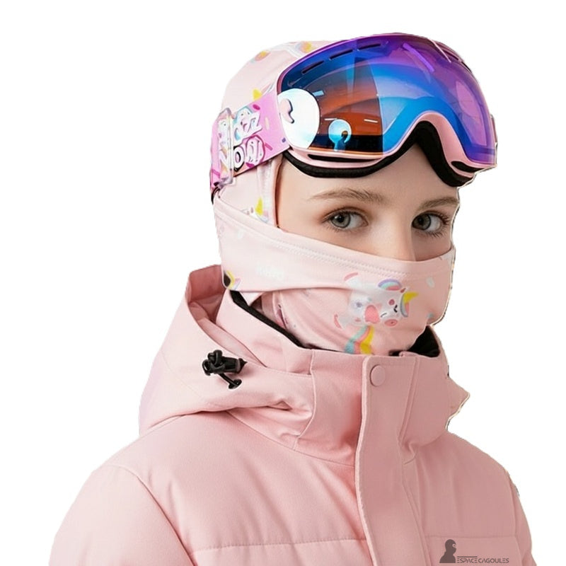 Cagoule ski fille rose portée sous un casque et des lunettes de ski, mettant en avant l’ajustement parfait et la compatibilité avec les équipements de sport d’hiver.
