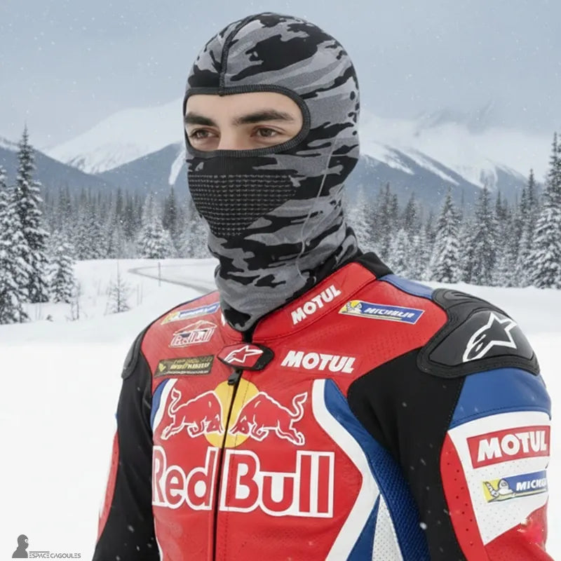 Cagoule sous casque en polyester et spandex de forme ajustée avec ouverture pour les yeux, vue portée par un motard en environnement hivernal enneigé - Espace Cagoules
