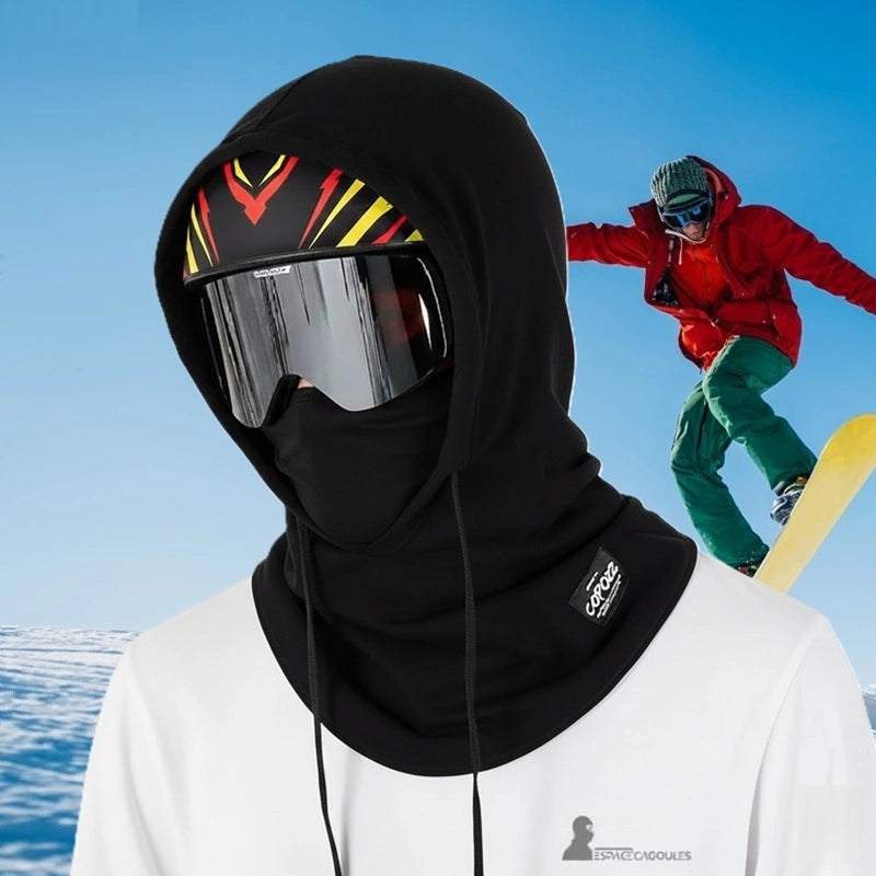 Cagoule sur casque de ski noire portée avec masque sur fond enneigé, snowboarder en arrière-plan, protection intégrale du visage et du cou - Espace Cagoules