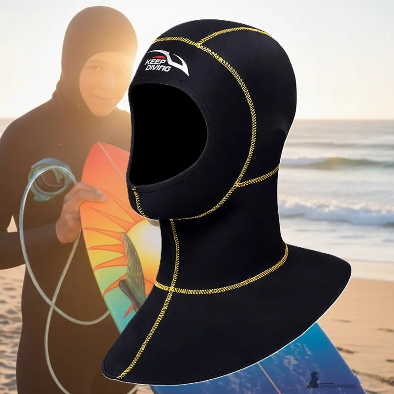 Women's black neoprene surf hood worn on the beach, covering the head and neck for surfing in cold water.