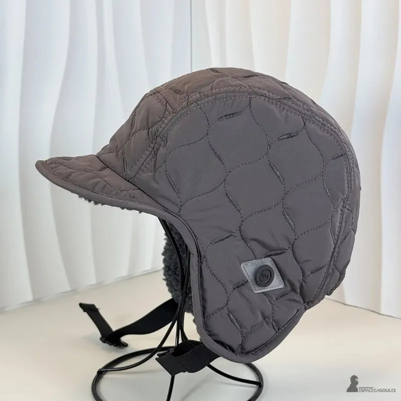 Casquette Chapka matelassée grise sur socle, vue latérale montrant tissu capitonné et oreillettes longues - Espace Cagoules