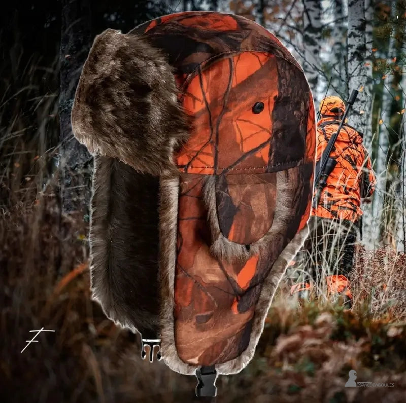 Chapka Chasse camouflage orange portée par un chasseur en forêt avec fusil