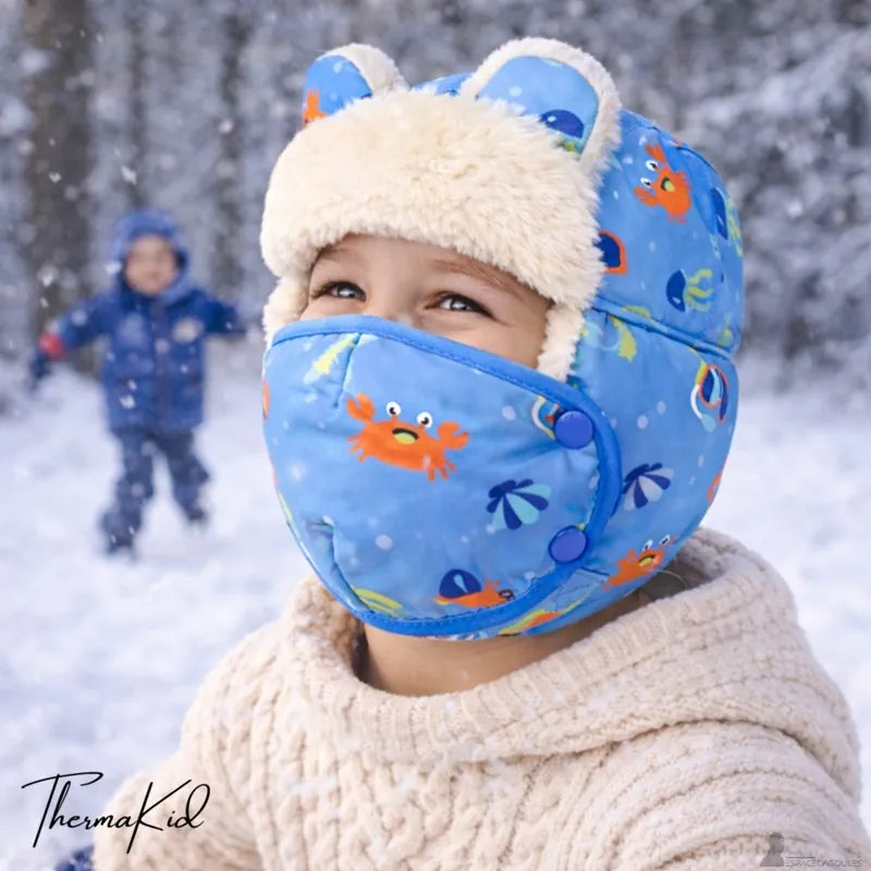 Chapka enfant garçon avec masque bleu à motifs marins portée en extérieur neigeux avec enfant en arrière-plan - Espace Cagoules