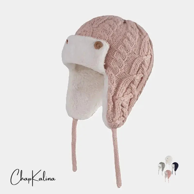 Chapka Enfant Tricot rose clair avec intérieur polaire blanc et attaches – Une chapka en tricot rose clair avec un motif torsadé élégant, doublée d’une polaire blanche ultra-douce. Des boutons en bois et des liens permettent un ajustement parfait pour protéger du froid.