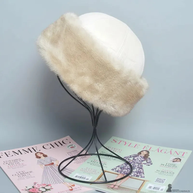 Faux fourrure Chapka in beiger Kunstfell mit weißem Oberteil, strukturierte Chapka-Form, Seitenansicht auf Ständer, in Innenräumen vor neutralem Hintergrund präsentiert - Espace Cagoules