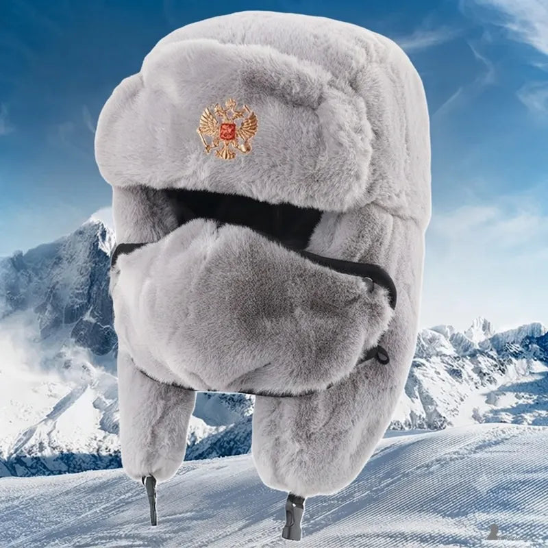 Chapka russe impériale gris clair en fourrure avec insigne doré, présentée sur un décor de montagne enneigée - Espace Cagoules