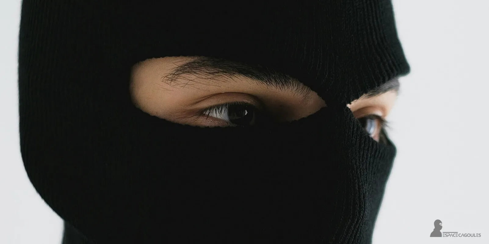 Cagoule 2 trous noire en maille épaisse, gros plan sur le regard d’un homme, ouverture autour des yeux, balaclava ajustée et confortable.