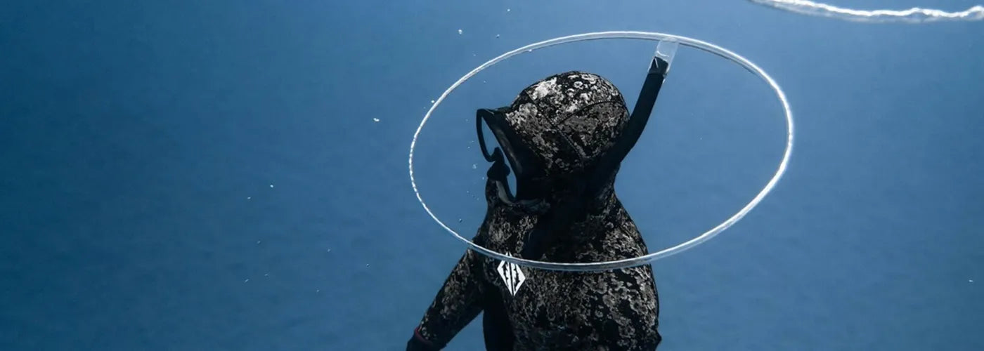 Apnéiste en combinaison camouflage et cagoule intégrale, évoluant paisiblement dans les profondeurs bleues – Cagoule de Plongée Espace Cagoules