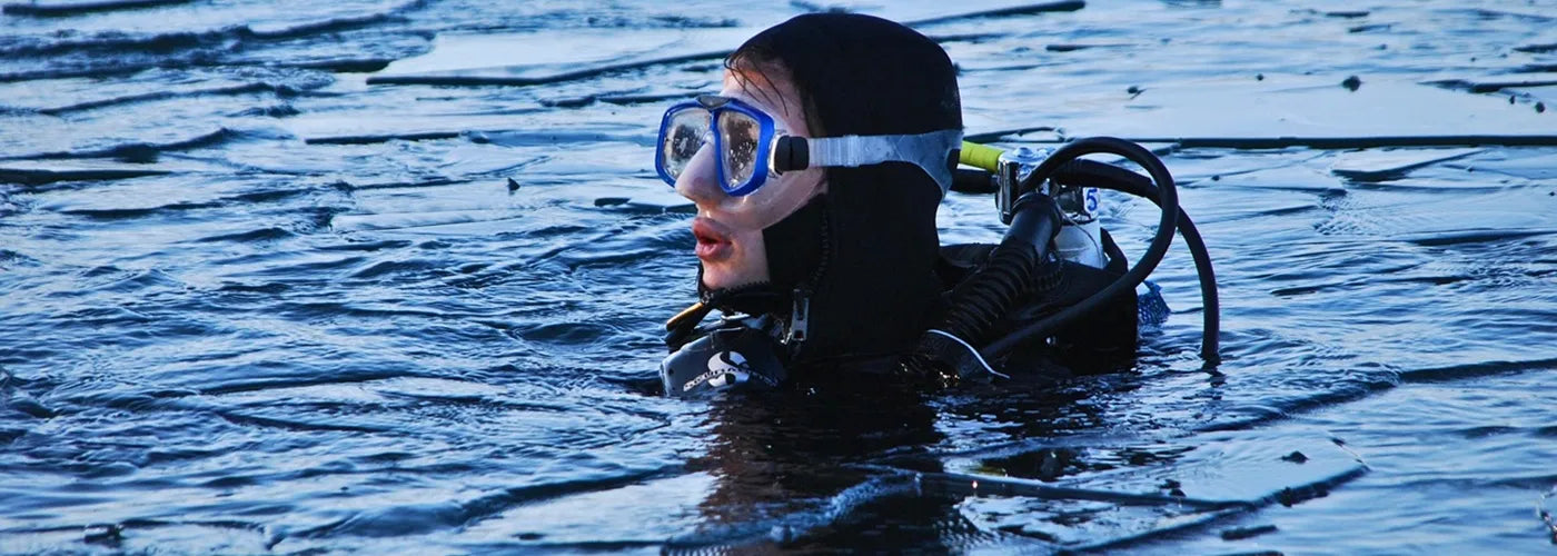 Plongeur en surface portant une cagoule néoprène noire et un masque bleu, prêt à explorer les fonds marins – Cagoule de Plongée Espace Cagoules