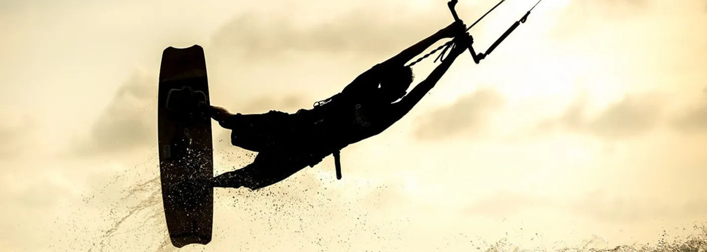 urfeur en plein saut sur l’eau au coucher du soleil, silhouette sportive capturant l’énergie du surf – Cagoule de Surf Espace Cagoules