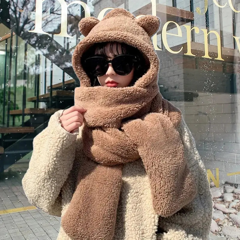 Écharpe cagoule pour femme en polaire marron avec des oreilles d'ours, associée à des lunettes de soleil noires pour un look chic et chaleureux en hiver. Parfaite pour une protection optimale contre le froid.