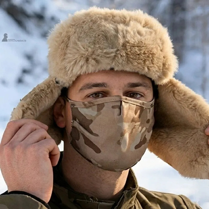 Ouchanka avec masque camouflage désert portée par un homme en extérieur enneigé vue de face avec rabats relevés et masque couvrant le nez et la bouche - Espace Cagoules