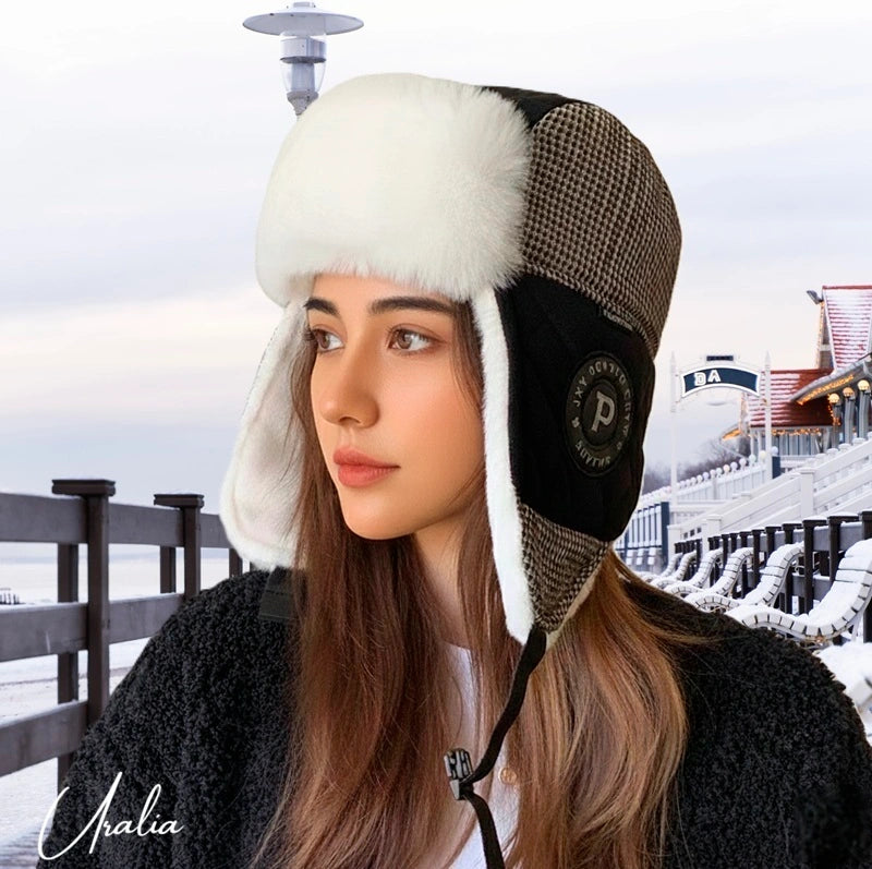 Ouchanka femme portée en extérieur, chapka hivernale en matière polaire avec cache-oreilles épais, forme enveloppante et design structuré, vue trois quarts sur fond enneigé d'une terrasse de café - Espace Cagoules