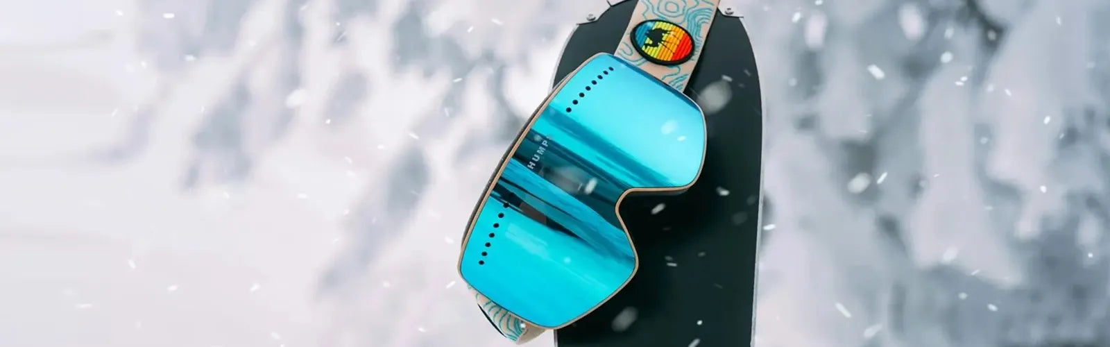 Masque de ski bleu accroché à une planche dans la neige, illustrant la collection Cagoules Ski – Espace Cagoules