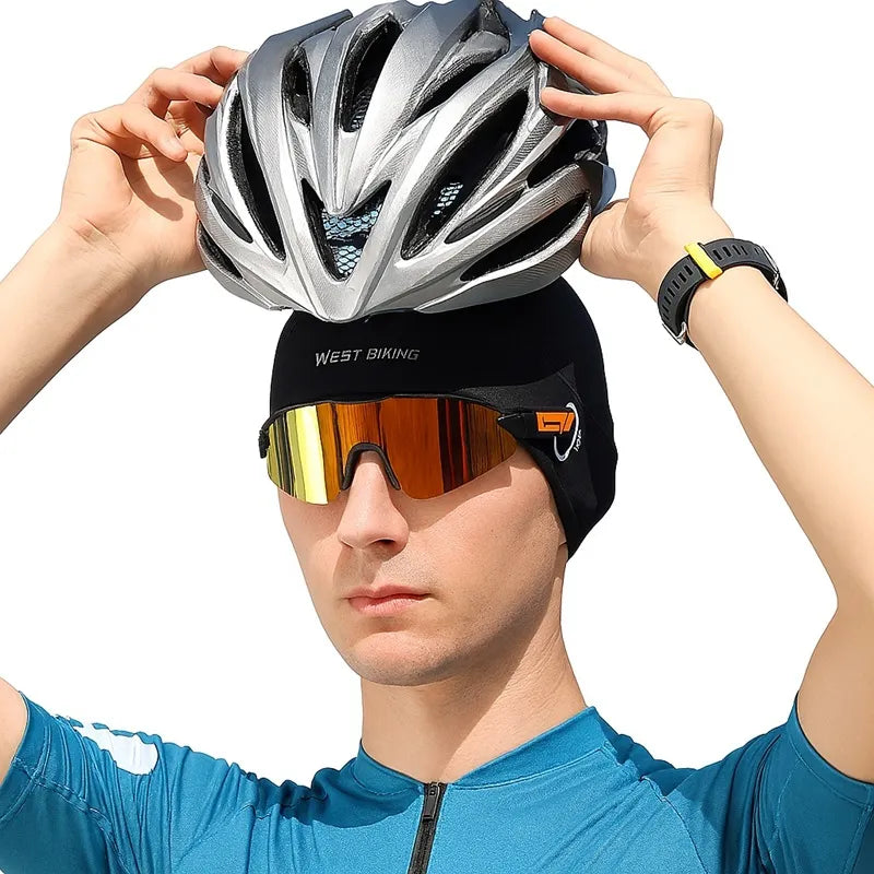 Cycliste portant un sous casque vélo été noir avec des lunettes de sport miroir, ajustant son casque de vélo gris. Accessoire respirant et léger, idéal pour l’été, assurant confort et absorption de la transpiration sous un casque.